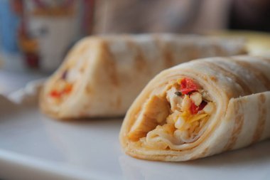 Dolgu ve dokuları gösteren beyaz bir tabağa iki paket konur..