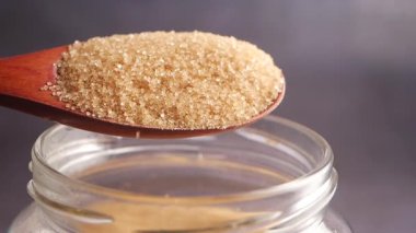 Kahverengi şeker, cam bir kavanozun üstündeki tahta kaşığa konur..