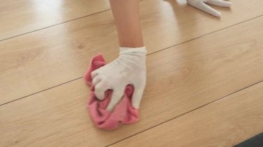 İnsan eldiven giyerken tahta zemini bezle siler..