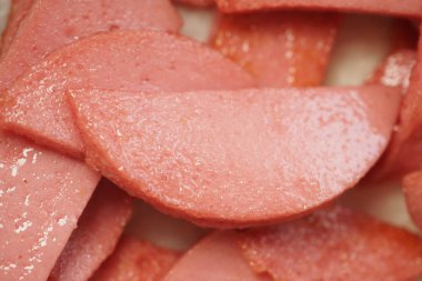 Mutfaktaki kesme tahtasının üzerinde pembe işlenmiş et parçaları var..