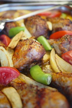 Patates ve biberli tavuk parçaları bir tepside dizilir..