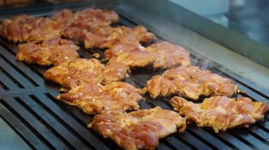 İnsanlar yoğun bir mutfakta ızgarada tavuk pişiriyor..