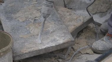 İşçiler zemindeki betonu kırmak için matkap ve araçlar kullanıyorlar.