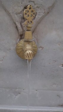 Gündüz vakti halka açık bir alanda pirinç musluktan su akar.