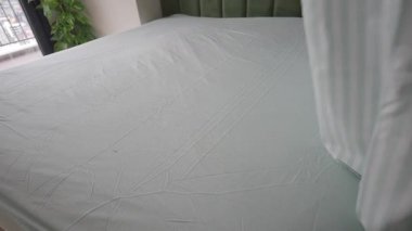 Parlak bir odada temiz çarşaflı bir yatak yapan bir insan..