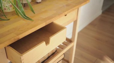 Açık çekmecesi olan ahşap bir masa iyi aydınlatılmış bir yerde gösterilir..