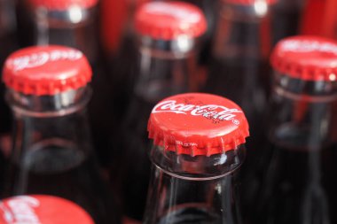 Bir markette bir şişe Coca-Cola bir masanın üzerinde oturur. Kapaklar parlak kırmızı..