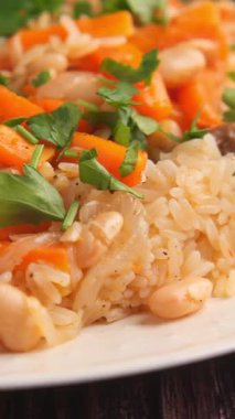 Bir insan pirinci renkli sebzelerle ve taze otlarla hazırlar..