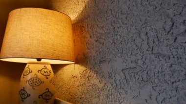 Bir lamba kaba bir duvara ışık yayar, desen ve tasarımı gösterir.