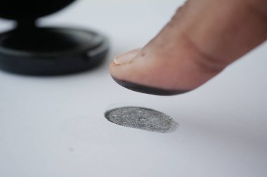 Bir insan parmak izini almak için mürekkep yastığına parmağını basar..