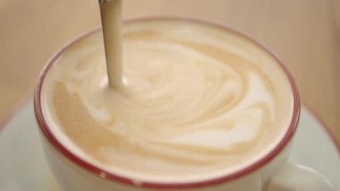 Bir insan kahveye süt döker köpük ve desenler yaratır..