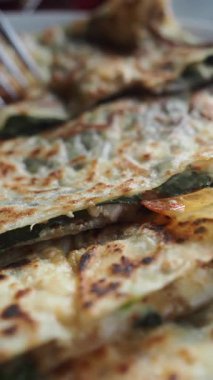 Bir kişi çeşitli dolgularla düz ekmek hazırlar ve pişirir..