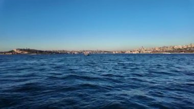 Şehir silüeti, berrak sularda hareket eden bir tekneden görülebilir..