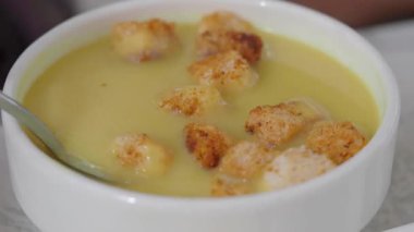 Bir kaşık, beyaz bir kaseden sıcak çorba kaldırır..