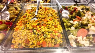 Müşteriler bir restorandaki açık büfede kendilerine taze sebze ikram ederler..