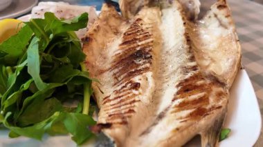 Restoranda salata ve limonla servis edilen ızgara balık tabağı..