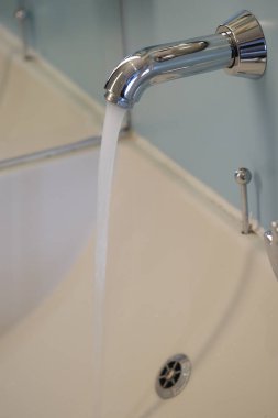 Musluktan akan su banyodaki beyaz lavaboya akıyor..