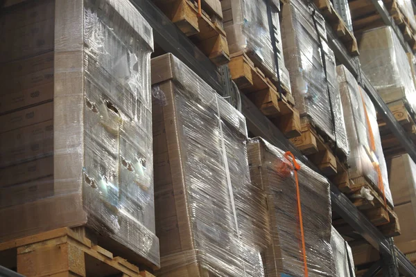 İşçiler, yoğun bir depoda paletler üzerinde mal organize ederler..