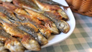 Kızarmış balık bir tabağa konur ve yanında servis için bir sepet vardır..