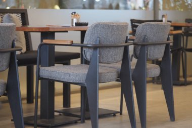 Sandalyeler ve masalar bir kafede hazır ve içeride insanlar var..