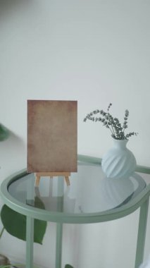 Basit bir çerçeve bir vazonun yanındaki yeşil bir masada duruyor..