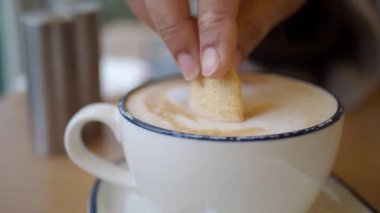 Sabahları bir kafede bir el kurabiyeyi bir fincan kahveye batırır..