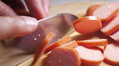 Aşçı, mutfaktaki tahta kesme tahtasının üzerinde sosis doğruyor..