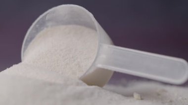 Bir ölçüm kepçesinde bir yüzeye dökülen protein tozunun yakın görüntüsü.