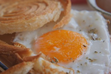 Bir tabak ekmek dilimlerinin yanında kızarmış yumurta ve rulo..