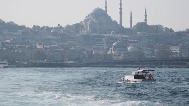 İstanbul 'da arka planda cami olan bir tekne suda ilerliyor..