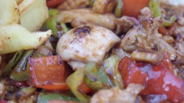 Tavuk, dolmalık biber ve soğan karışımı baharatlarla pişirilir..