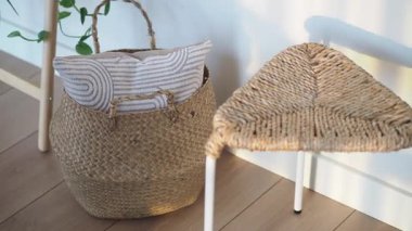 Dokuma sepetinin yanında bir sandalye olan bir odada yastık var..