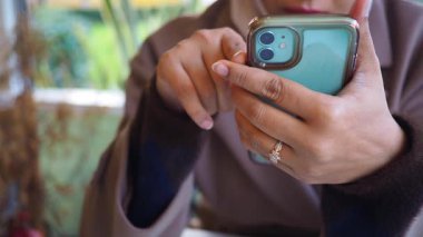 Bir kadın bir kafede otururken akıllı telefonuna odaklanır..