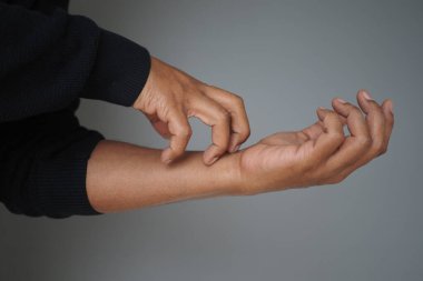 Kapalı bir alanda bir insan kolunu kaşıyor..