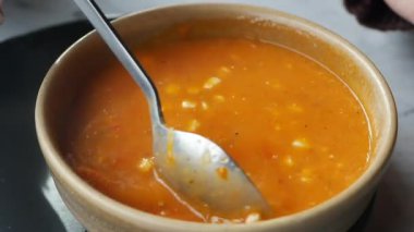 Bir tencere domates çorbası sıcak bir mutfakta kaşıkla karıştırılıyor..