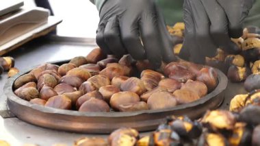 İnsanlar sonbaharda bir sokak standında kavrulmuş kestane sever..