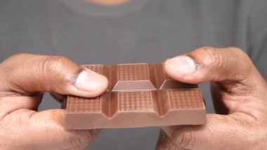 Bir insan çikolatayı yakın çekimde kırar..