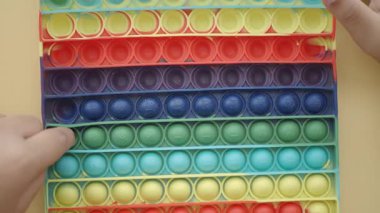 İki el sarı arka planda renkli bir oyuncağa basar.