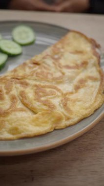 Yanında salatalık dilimleri olan bir tabakta omlet servis edilir..