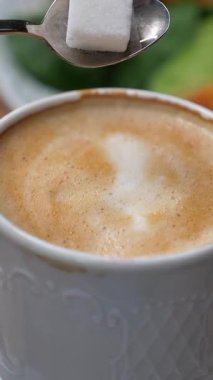 Bir insan sabah saatlerinde kahveye şeker ekler..