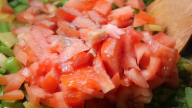 Domates doğrayıp mutfakta yeşil sebzelerle karıştırmak..