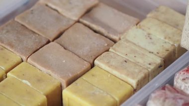 İnsanlar bir pazar ortamında çeşitli sabun bloklarını kontrol ediyorlar..