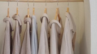 Birkaç açık renkli gömlek bir odada askıda asılı duruyor..