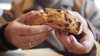 Pastanede arkadaşlarıyla konuşurken elinde kurabiye tutan kişi.