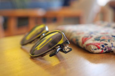 Güneş gözlükleri yakınlarda desenli bir bezle bir masanın üzerine konur..