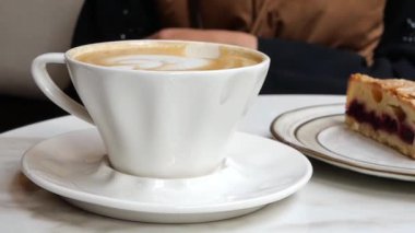 Kişi kahve içer ve rahat bir kafe ortamında kek yer..