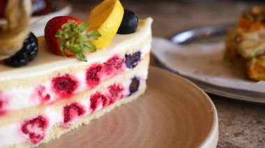 Birisi bir kafede meyveli bir dilim pastayı ısırıyor..