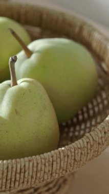 Yeşil armutlar, kapalı bir masada duran bir sepette dinleniyor..