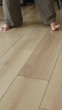 Bir insan çıplak ayakla ahşap zemini paspaslıyor..