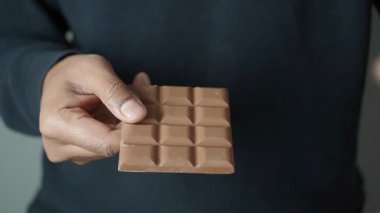 Bir insan elinde çikolatayla şekere odaklanır..